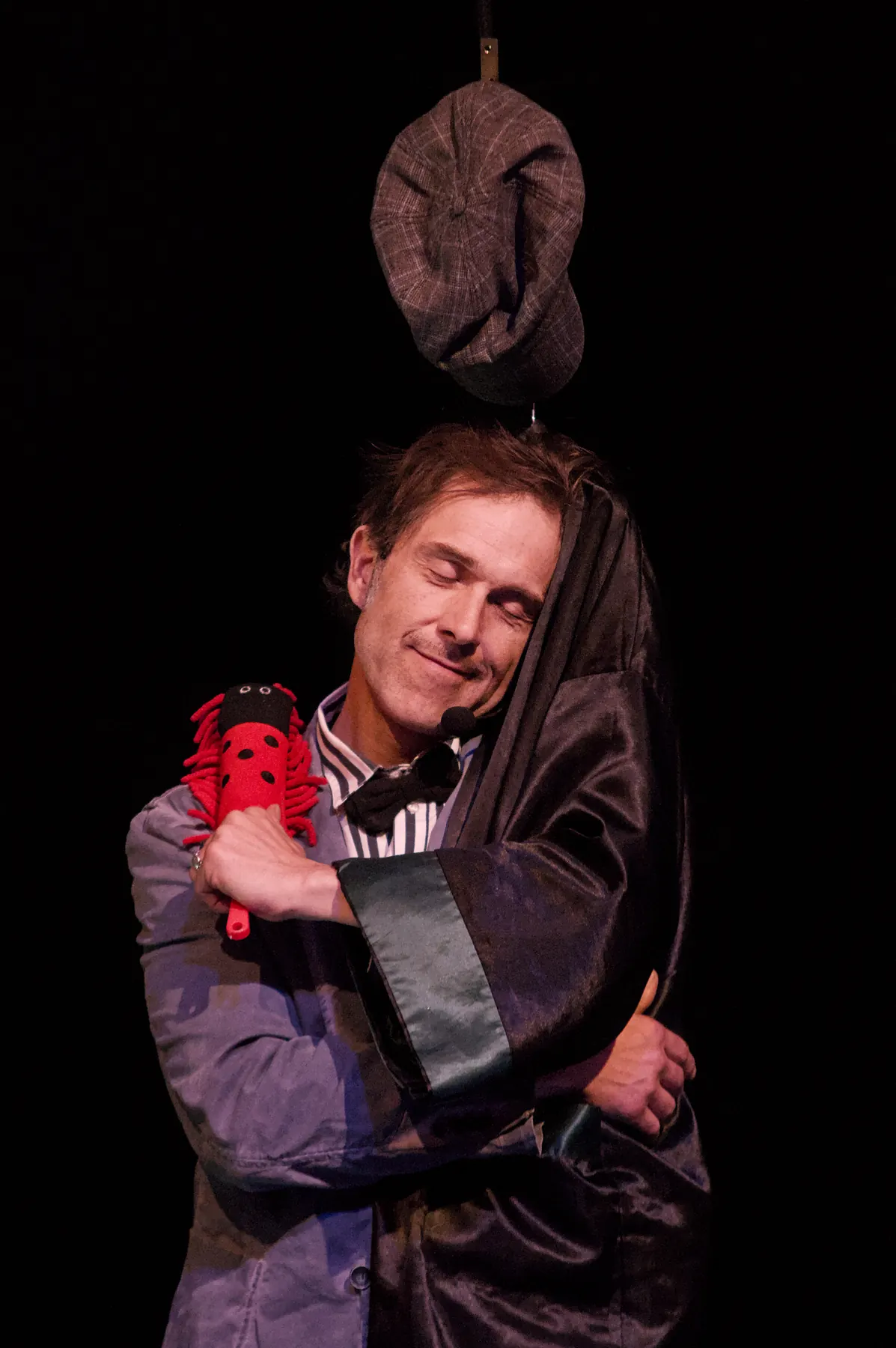 The clown hugging a red fabric ladybird, smiling with his eyes closed