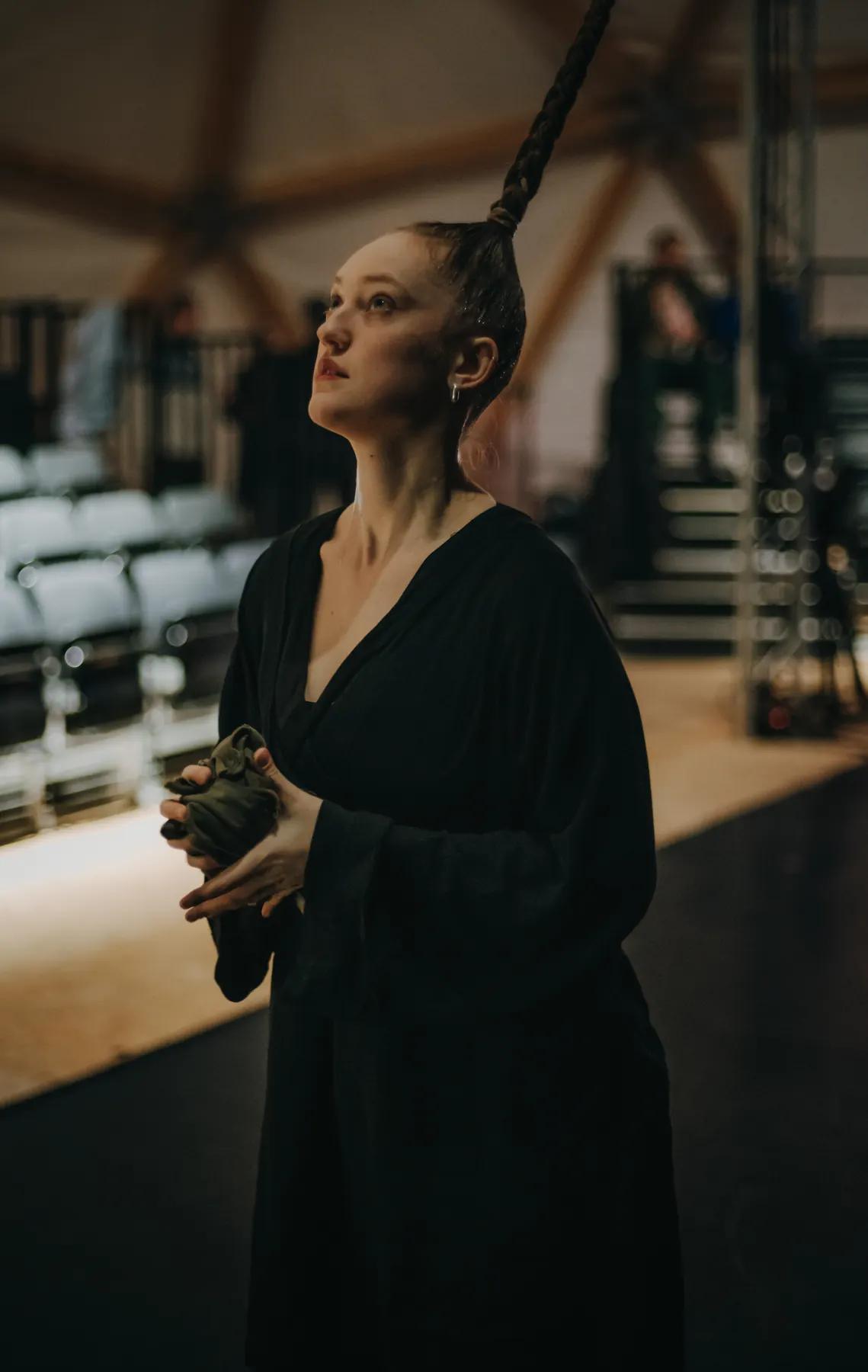 Artist in a black robe standing beside a hanging rope, looking upward