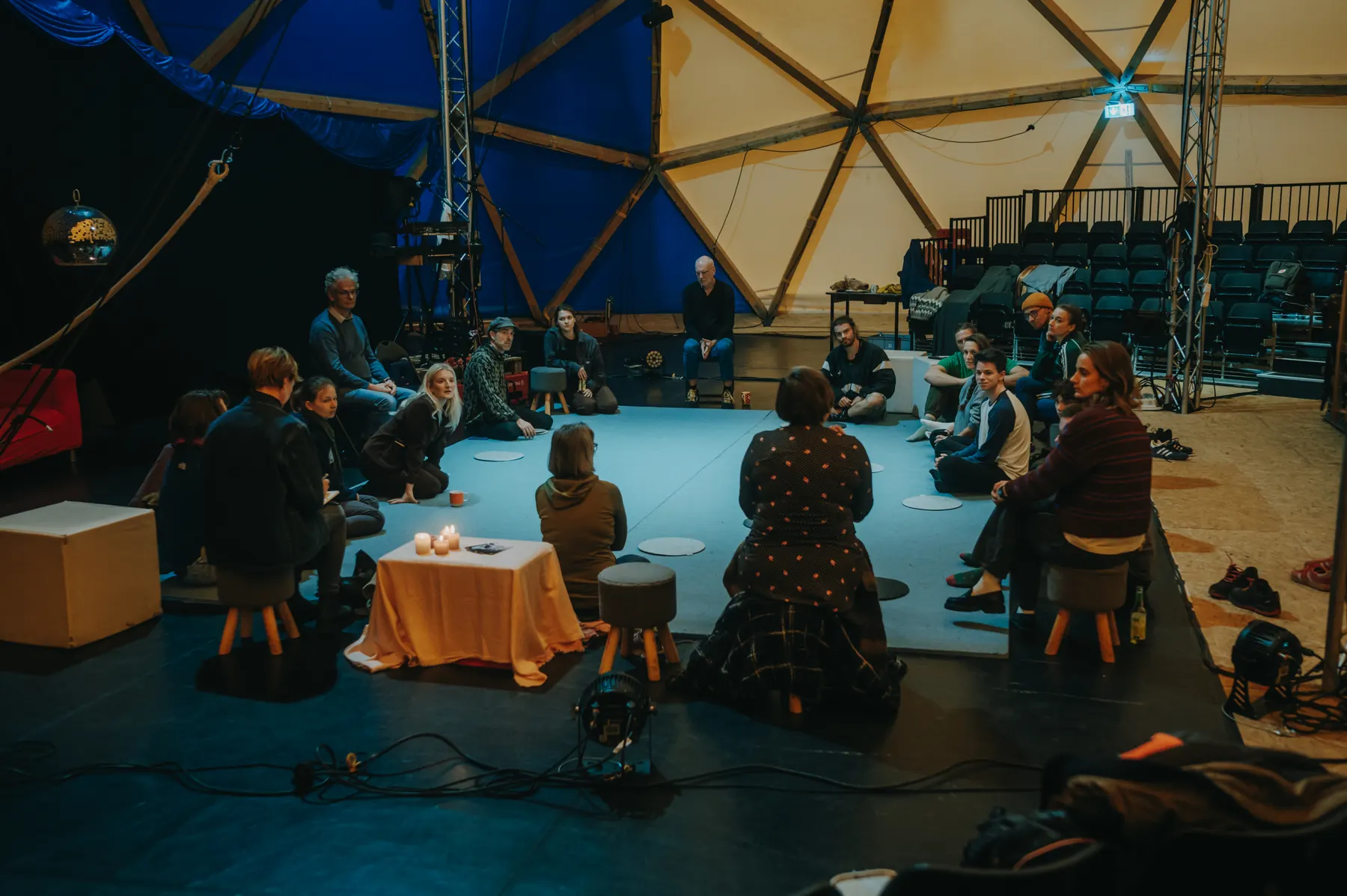 About twenty people sitting in a circle on the floor of the dome, a small table with candles in the middle