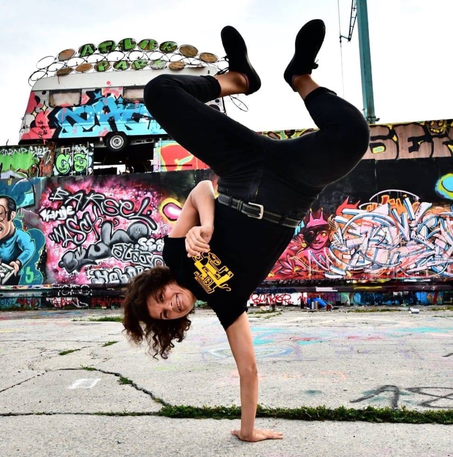 Frau im einarmigen Handstand vor einer Graffitiwand